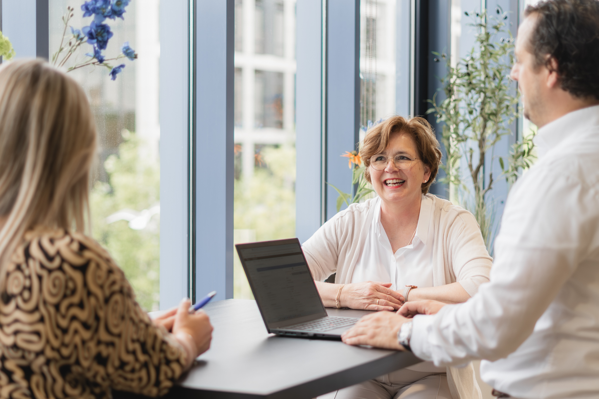 Drie mensen aan tafel met een laptop